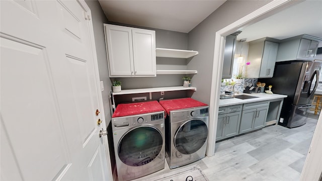 washroom featuring cabinets, independent washer and dryer, and sink