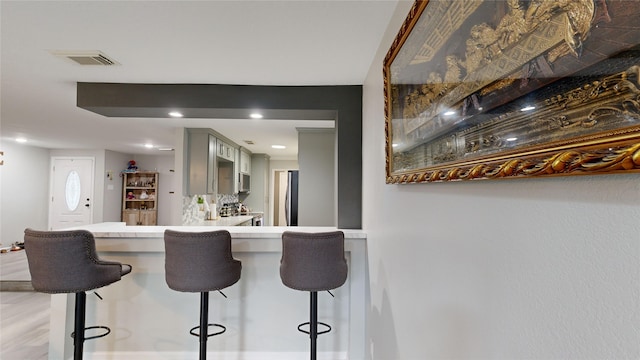 kitchen featuring gray cabinetry, kitchen peninsula, a breakfast bar area, and appliances with stainless steel finishes