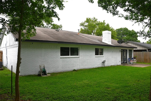 rear view of house with a lawn, central AC, and a patio