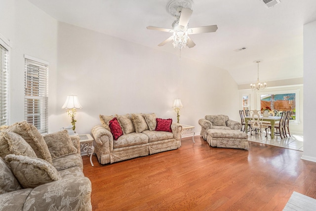 living room with lofted ceiling, hardwood / wood-style flooring, and ceiling fan with notable chandelier