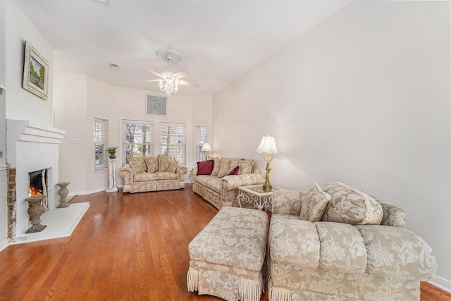 living room featuring ceiling fan, a fireplace, and hardwood / wood-style floors