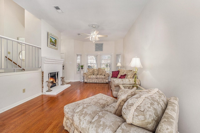 living room with hardwood / wood-style flooring, ceiling fan, and a fireplace