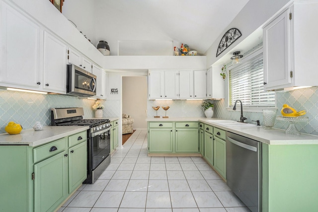 kitchen featuring white cabinetry, green cabinets, stainless steel appliances, and vaulted ceiling