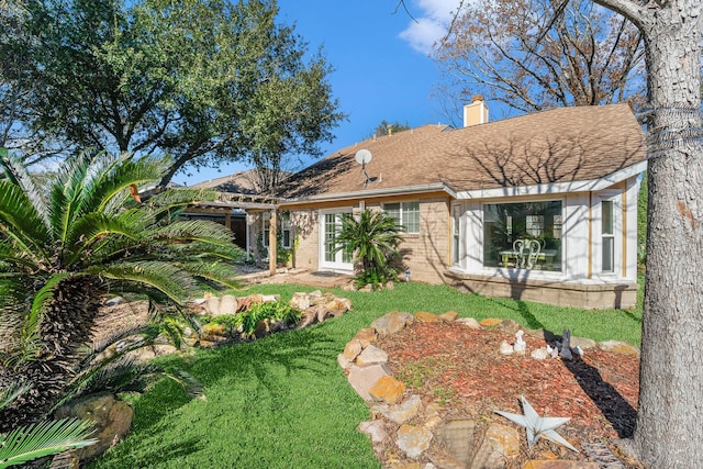 rear view of house featuring french doors and a lawn