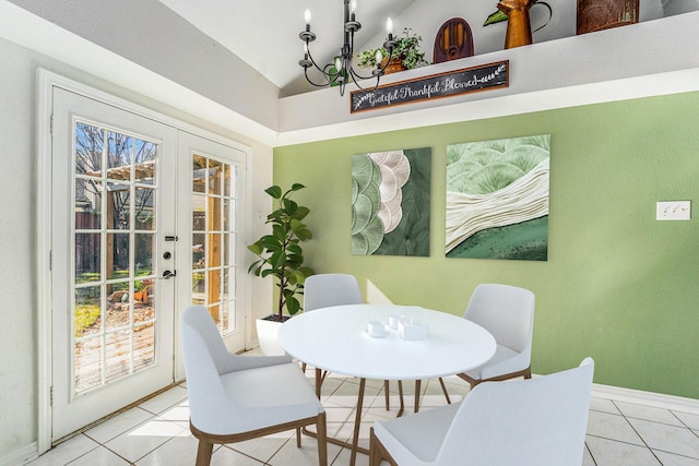 tiled dining space with vaulted ceiling, an inviting chandelier, and french doors