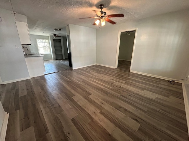 unfurnished living room with a textured ceiling, dark hardwood / wood-style floors, ceiling fan, and sink