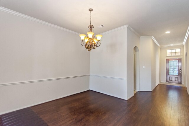 empty room featuring ornamental molding, dark wood-type flooring, and an inviting chandelier