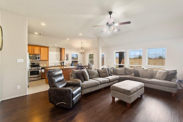 living room with ceiling fan with notable chandelier, wood-type flooring, and sink