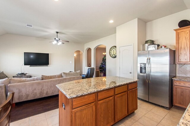 kitchen with a center island, lofted ceiling, ceiling fan, stainless steel fridge, and light tile patterned floors