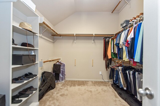 walk in closet with light carpet and vaulted ceiling