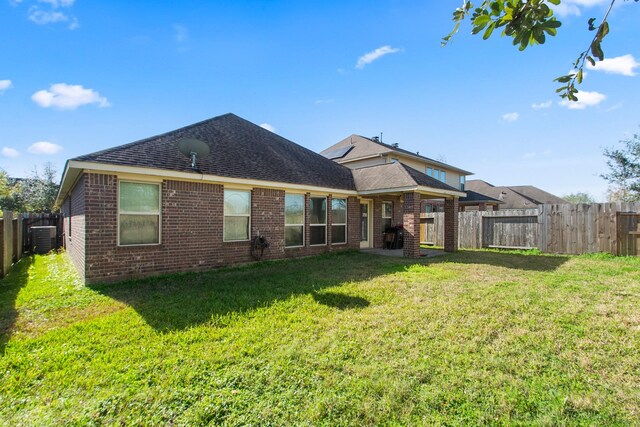 rear view of house featuring central AC and a yard