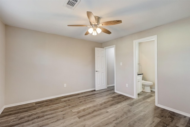 unfurnished bedroom featuring connected bathroom, hardwood / wood-style floors, and ceiling fan