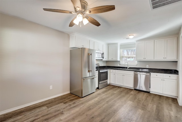 kitchen with sink, ceiling fan, stainless steel appliances, white cabinets, and light wood-type flooring