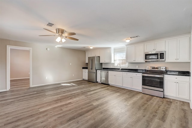 kitchen featuring appliances with stainless steel finishes, ceiling fan, sink, light hardwood / wood-style flooring, and white cabinetry