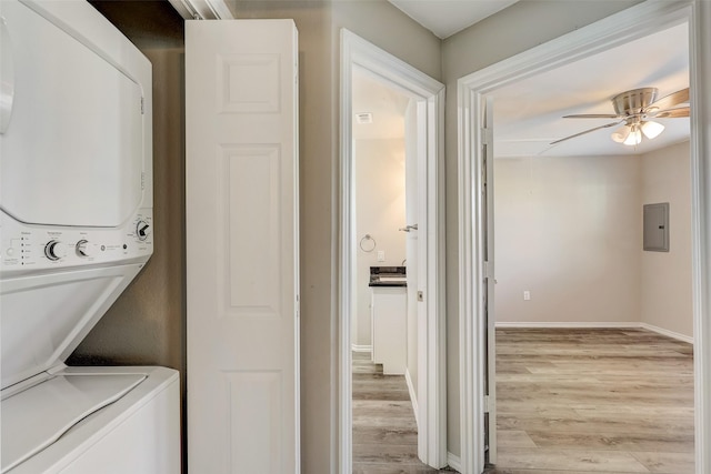 clothes washing area with stacked washer / drying machine, ceiling fan, electric panel, and light hardwood / wood-style flooring