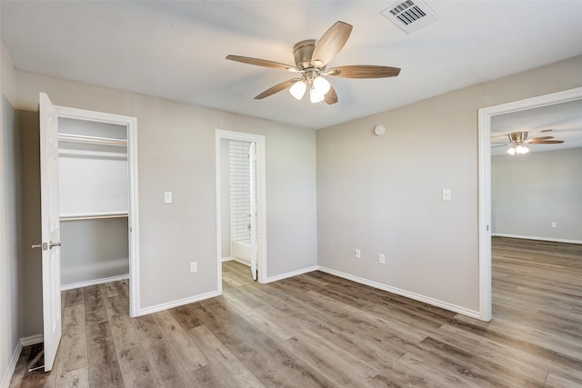 unfurnished bedroom featuring ceiling fan, light hardwood / wood-style floors, and a spacious closet