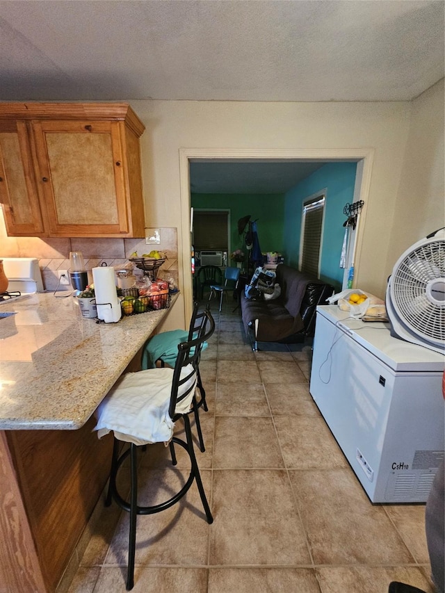 kitchen featuring washer / dryer, a textured ceiling, light tile patterned floors, and fridge