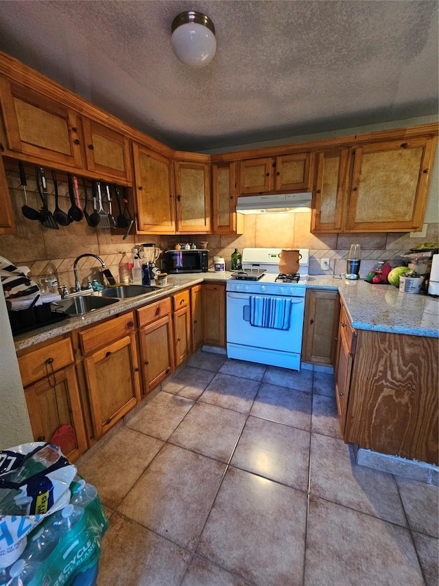 kitchen with gas range gas stove, sink, light stone counters, a textured ceiling, and light tile patterned floors