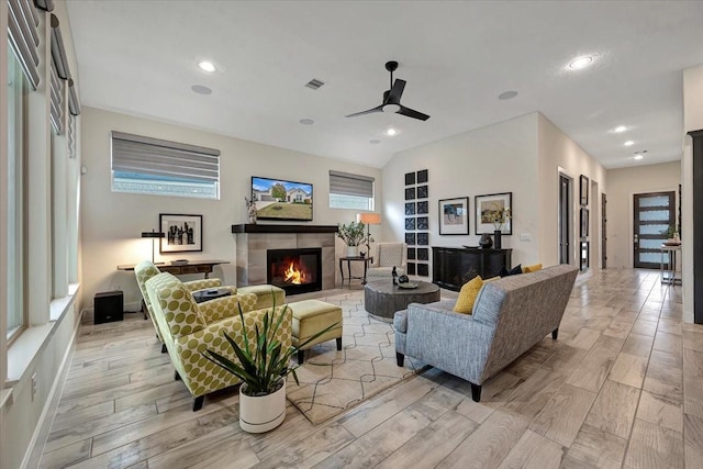 living room with a tile fireplace and ceiling fan