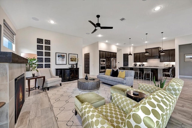 living room featuring ceiling fan, a fireplace, and light hardwood / wood-style floors