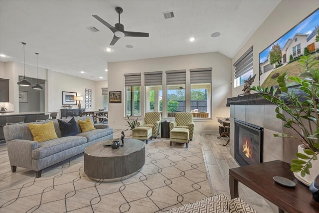 living room featuring a tile fireplace and ceiling fan