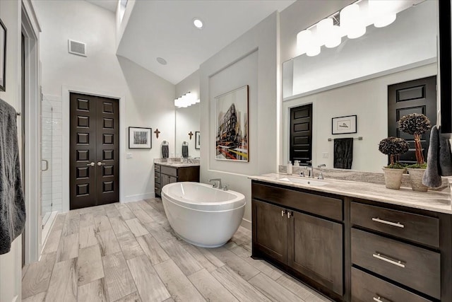 bathroom with plus walk in shower, vanity, and high vaulted ceiling