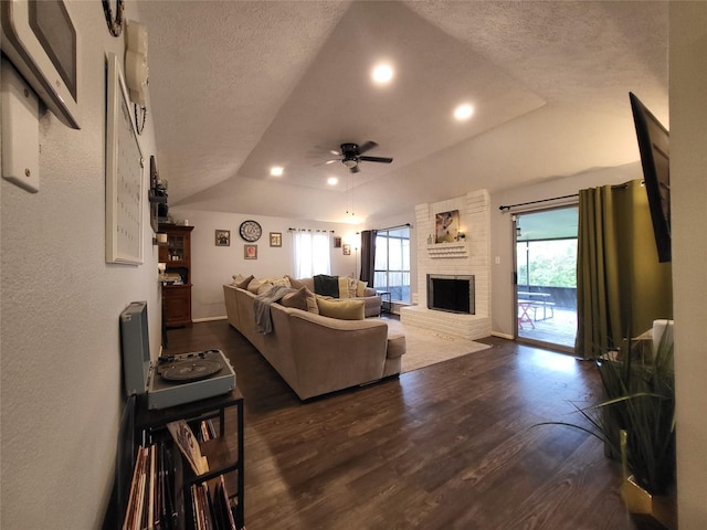 living room featuring dark hardwood / wood-style flooring, a brick fireplace, a textured ceiling, ceiling fan, and lofted ceiling