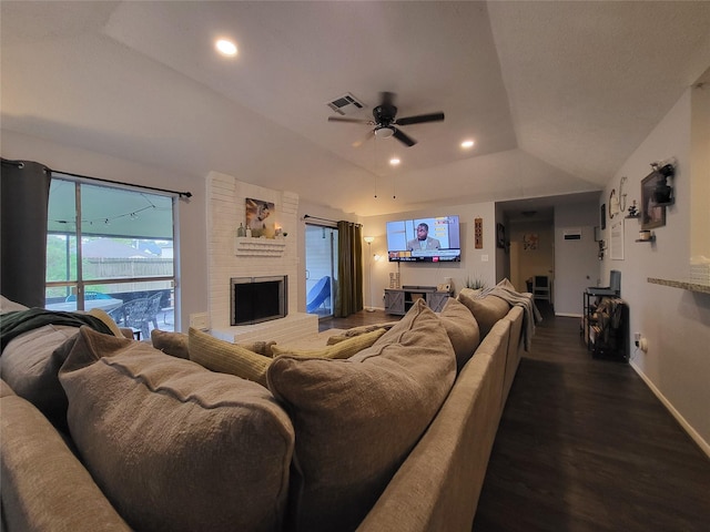 living room with ceiling fan, a brick fireplace, dark hardwood / wood-style floors, vaulted ceiling, and a tray ceiling