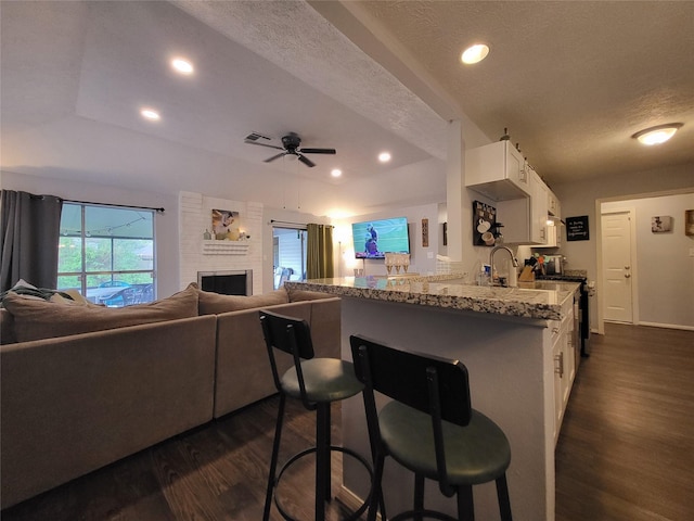 kitchen featuring a kitchen breakfast bar, light stone counters, white cabinetry, and a textured ceiling