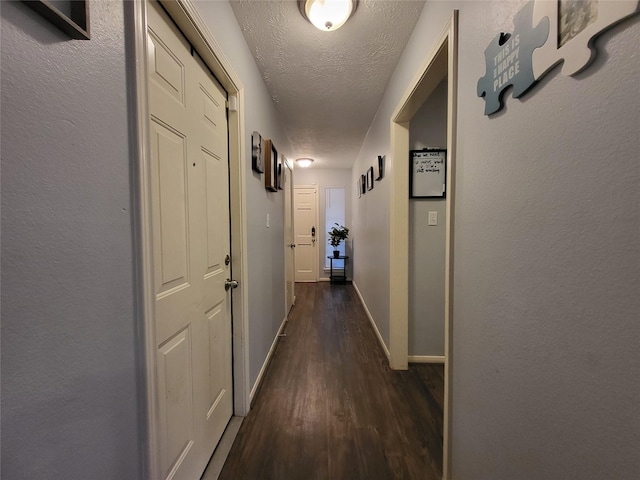 hallway with dark hardwood / wood-style flooring and a textured ceiling