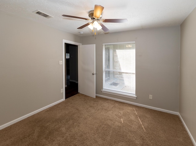 spare room featuring ceiling fan, carpet, and a textured ceiling