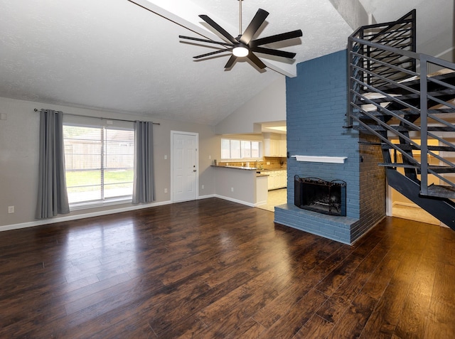 unfurnished living room with a fireplace, a textured ceiling, lofted ceiling with beams, and dark wood-type flooring