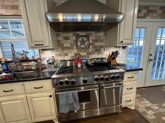 kitchen with french doors, white cabinetry, double oven range, and wall chimney range hood