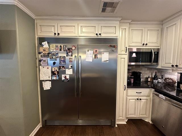 kitchen featuring appliances with stainless steel finishes, dark hardwood / wood-style flooring, tasteful backsplash, ornamental molding, and white cabinetry