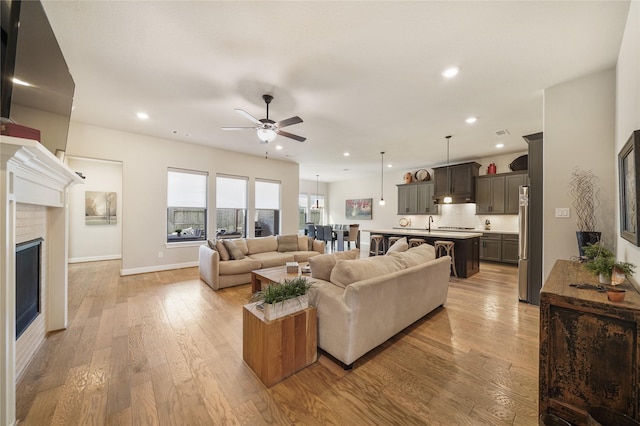 living room featuring ceiling fan, sink, and light hardwood / wood-style flooring