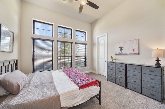 bedroom with ceiling fan, a high ceiling, and light carpet