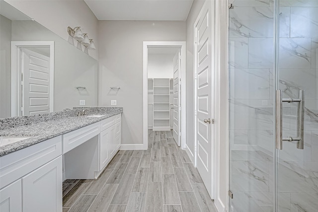 bathroom featuring a shower with door and vanity