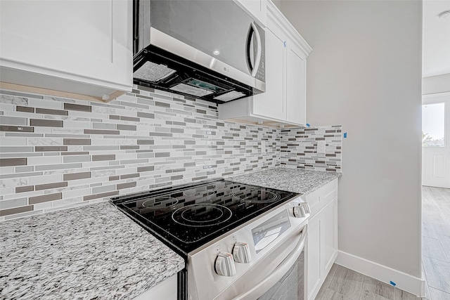 kitchen featuring light hardwood / wood-style flooring, range with electric stovetop, tasteful backsplash, light stone counters, and white cabinetry