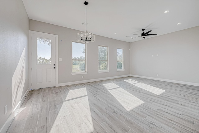 interior space featuring light hardwood / wood-style floors and ceiling fan with notable chandelier