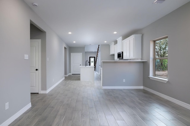 unfurnished living room featuring sink and light hardwood / wood-style floors