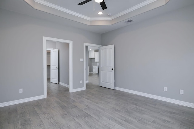 unfurnished bedroom with a raised ceiling, crown molding, ceiling fan, and light hardwood / wood-style flooring