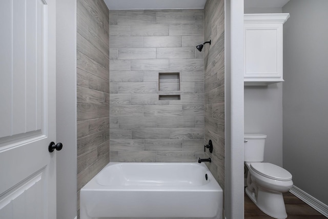 bathroom featuring hardwood / wood-style flooring, tiled shower / bath, and toilet