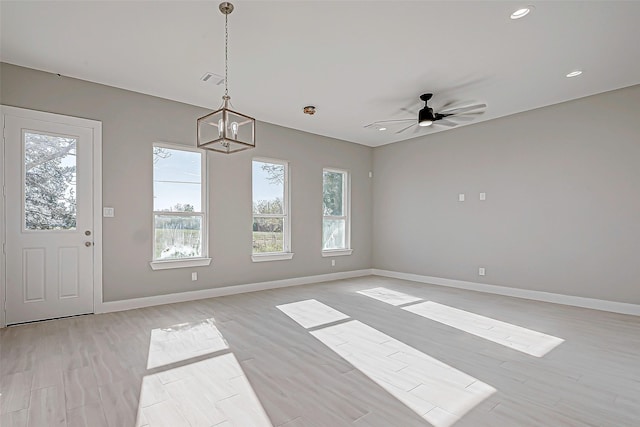 unfurnished room with ceiling fan with notable chandelier and light wood-type flooring