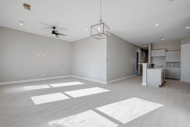 unfurnished living room with ceiling fan, sink, and light hardwood / wood-style flooring