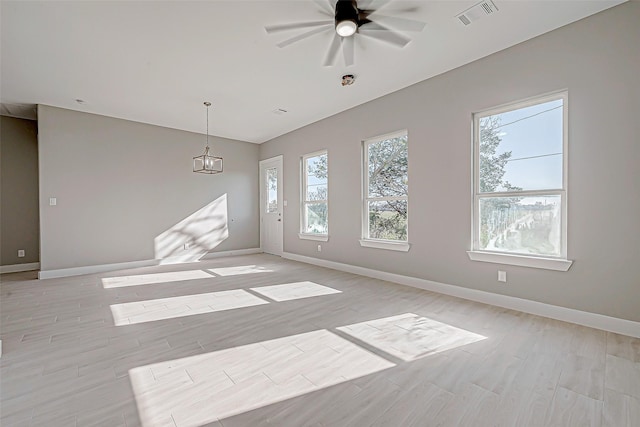 unfurnished room with ceiling fan with notable chandelier and light hardwood / wood-style floors