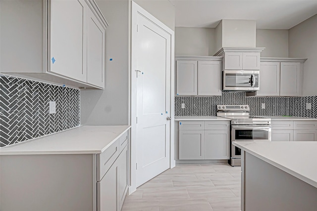 kitchen with gray cabinetry, stainless steel appliances, and tasteful backsplash