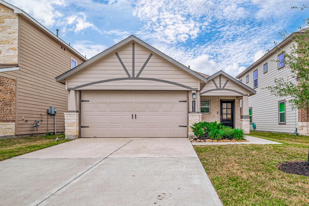 6830 Escondido Dr, Rosharon, TX 77583 - view of front of home featuring a garage, brick siding, concrete driveway, stone siding, and a front lawn