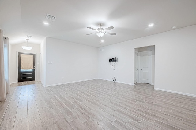 spare room with lofted ceiling, visible vents, light wood-style floors, a ceiling fan, and baseboards