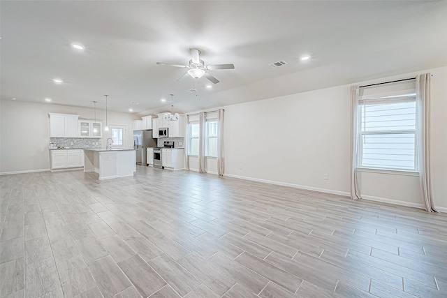 unfurnished living room with recessed lighting, a sink, visible vents, baseboards, and a ceiling fan