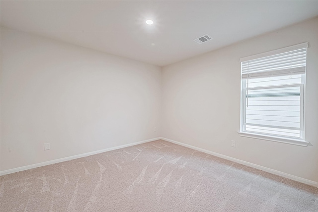 empty room featuring visible vents, baseboards, and light colored carpet